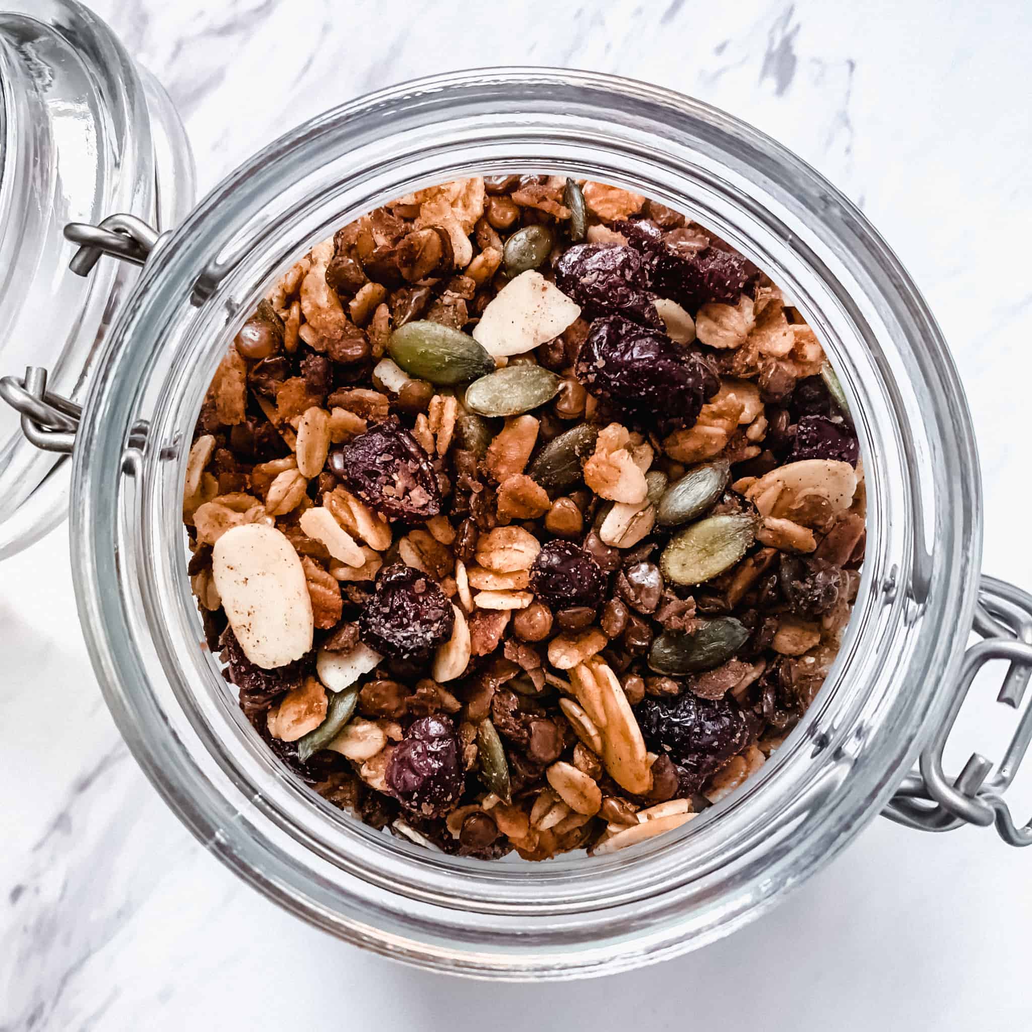 Close up shot of granola in a glass jar on a marble background.