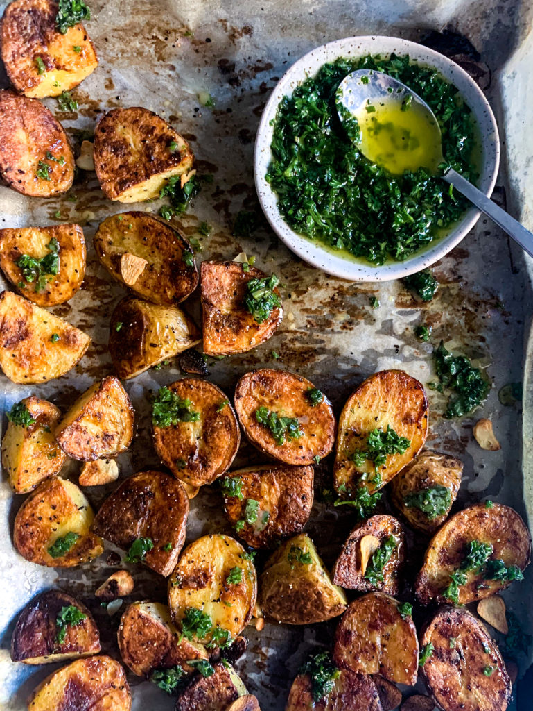 crispy roasted potatoes on a sheet pan with herb dressing