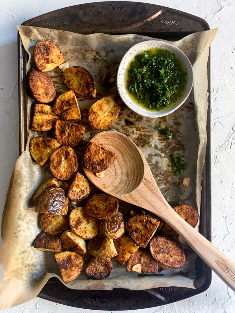 roasted potatoes on a sheet pan with a wooden spoon