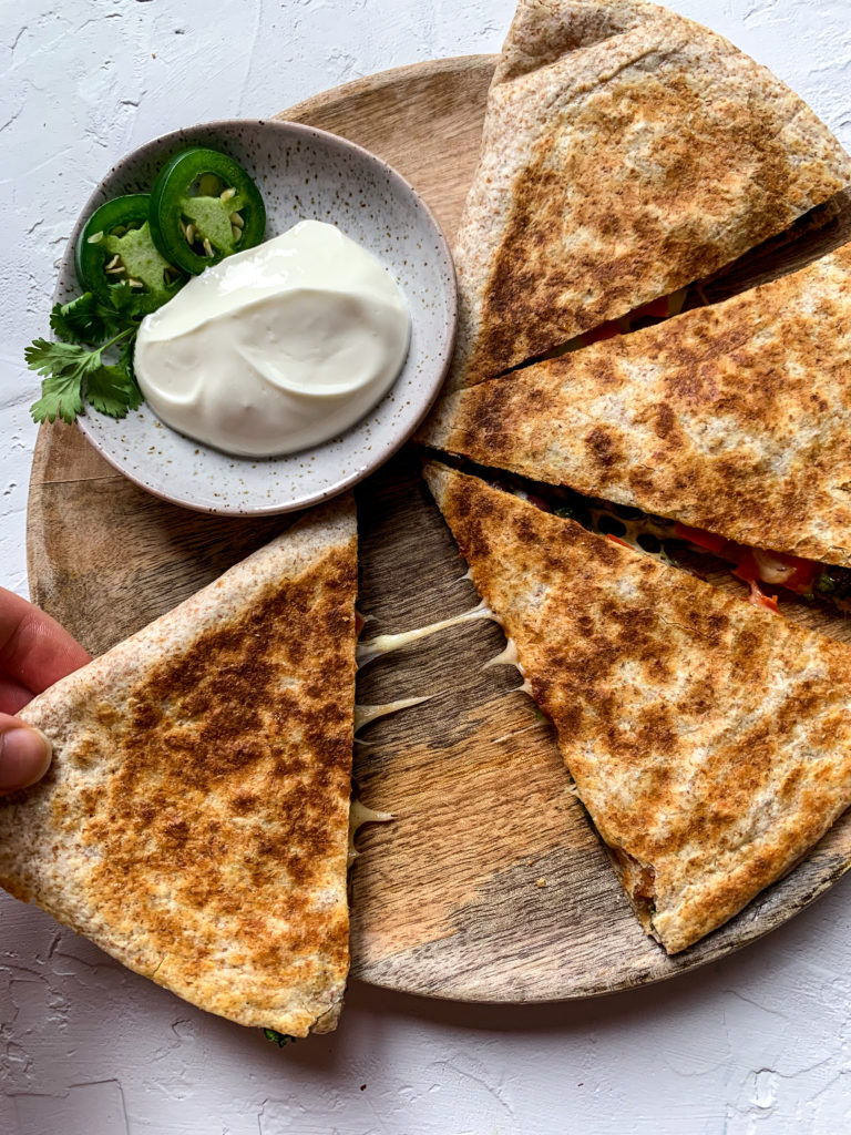 a slice of quesadilla being pulled away from the rest with a cheese pull