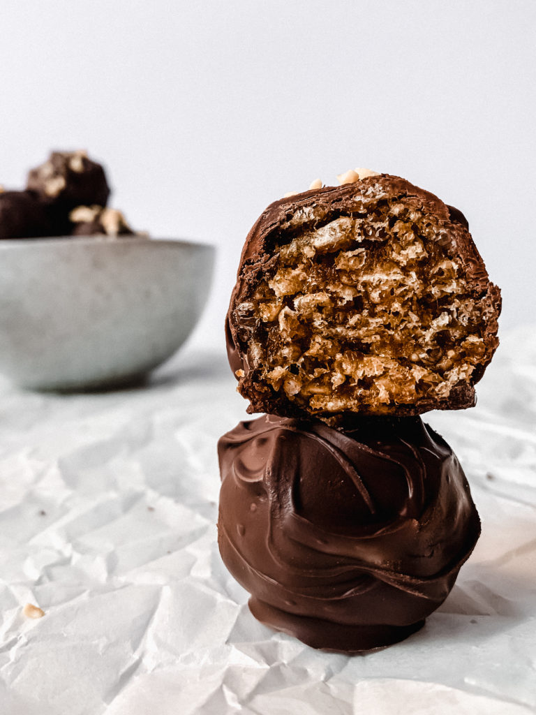 close up of two chocolate peanut butter date caramel balls stacked on top of each other