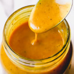 mango chutney vinaigrette dripping off spoon into a jar