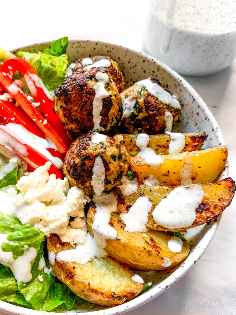 close up of creamy feta yogurt sauce drizzled over a greek pork meatball bowl