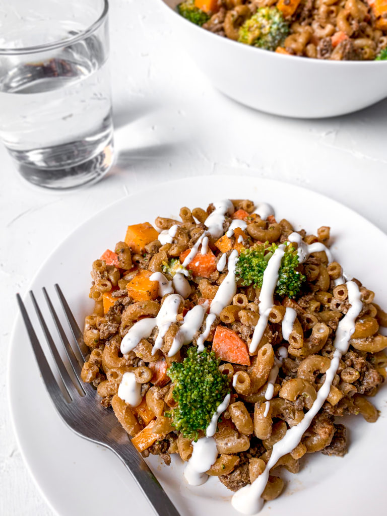 close-up of taco pasta salad on a white plate with a dressing drizzle