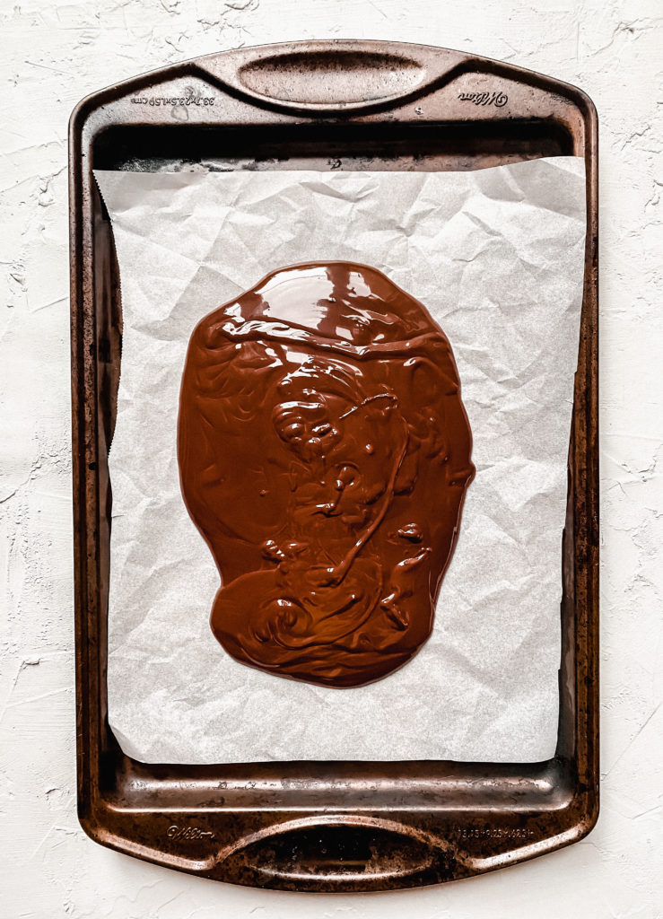 pool of chocolate poured onto a parchment lined baking sheet