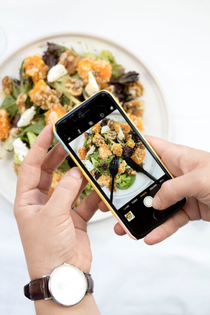 person taking photo of food on iphone