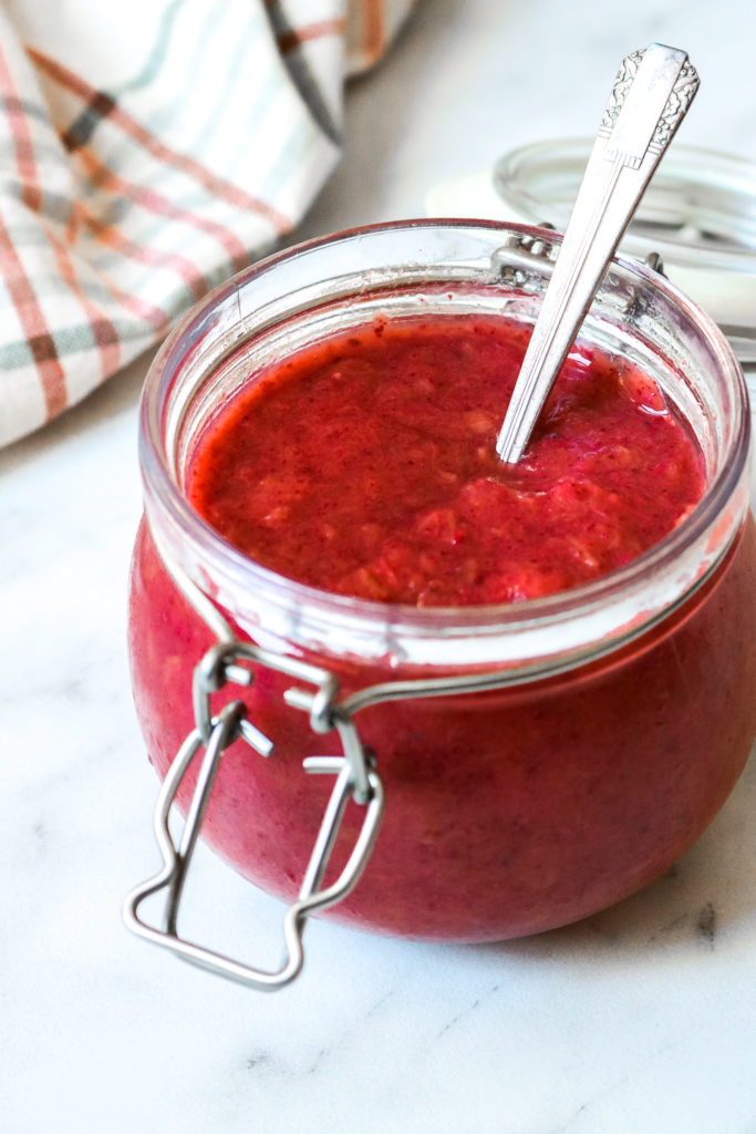 Strawberry rhubarb chia jam in a jar on a marble counter