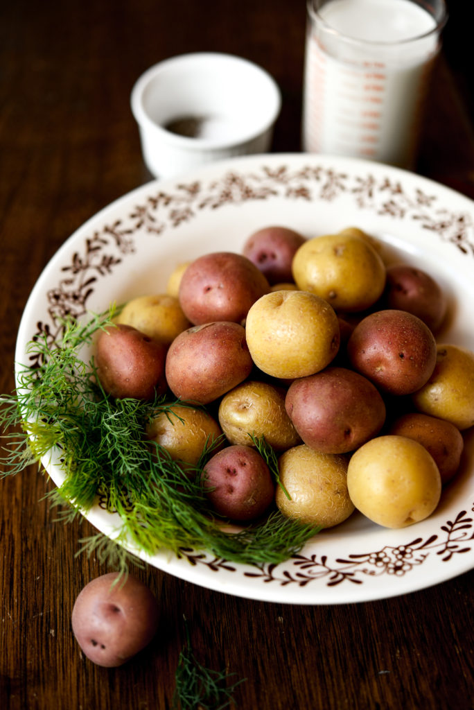 red and yellow new potatoes in a white bowl with fresh dill