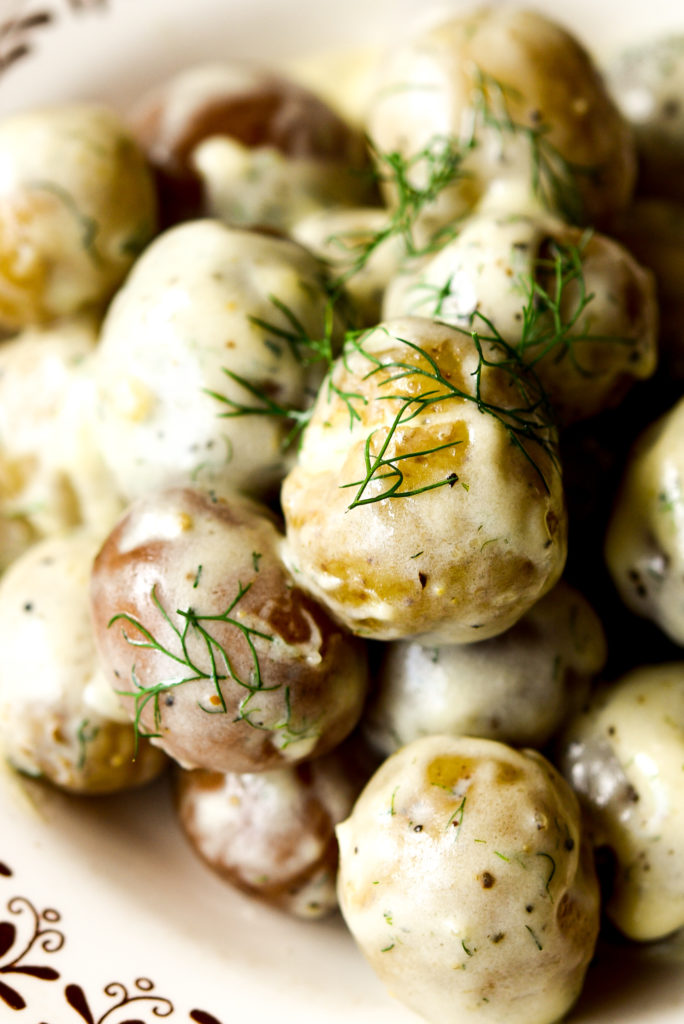 new potatoes in creamy sauce in a bowl topped with fresh dill