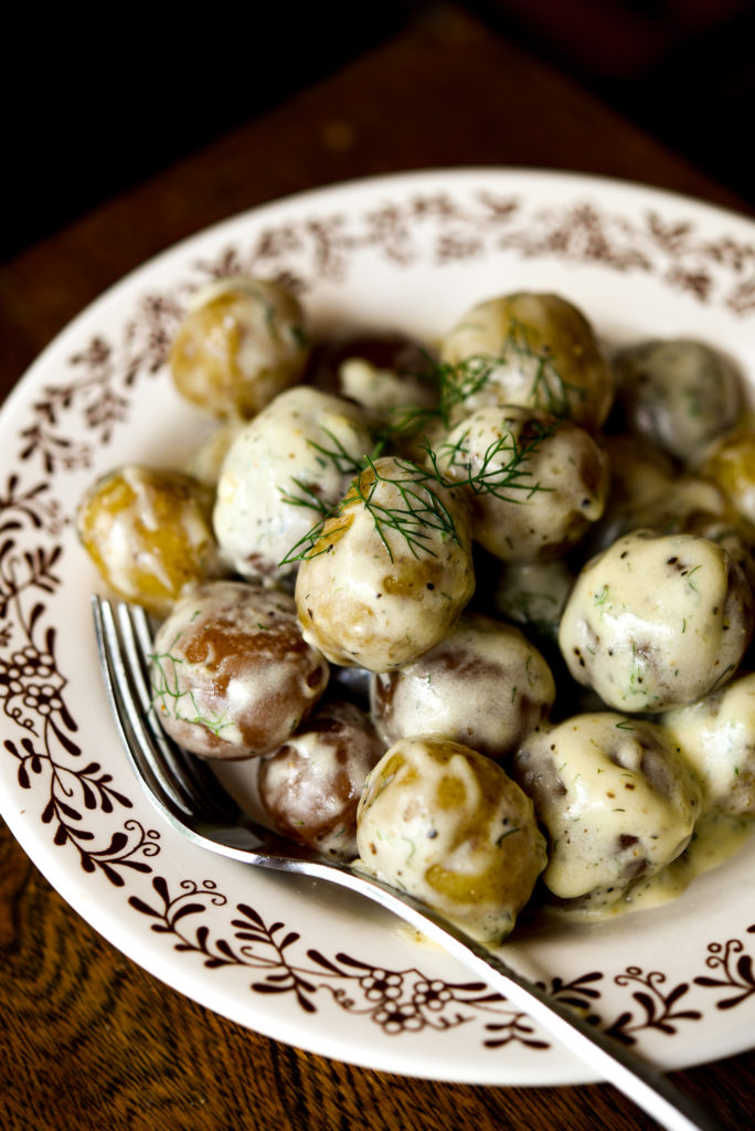 new potatoes in a creamy dill sauce in a bowl alongside a fork