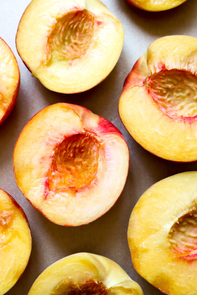 halved peaches on a baking sheet