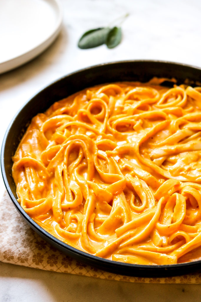 pumpkin alfredo in a frying pan sitting on a kitchen towel