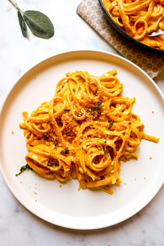 pumpkin alfredo swirled on a plate and topped with crispy sage breadcrumbs