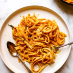 pumpkin alfredo on a beige plate with a fork and spoon