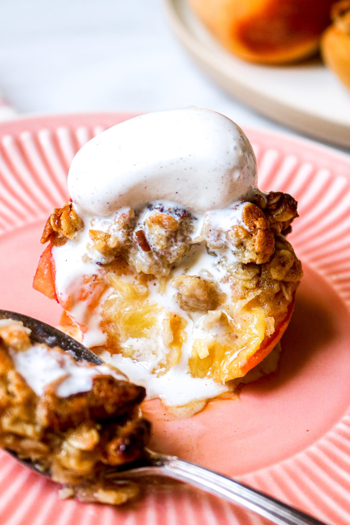 a baked peach with a bite taken out and melted vanilla ice cream running down it