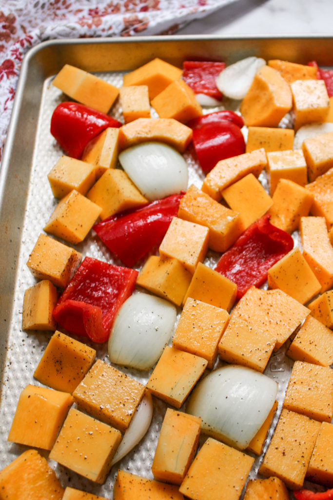 cubes of butternut squash, red peppers and onion on a metal baking tray
