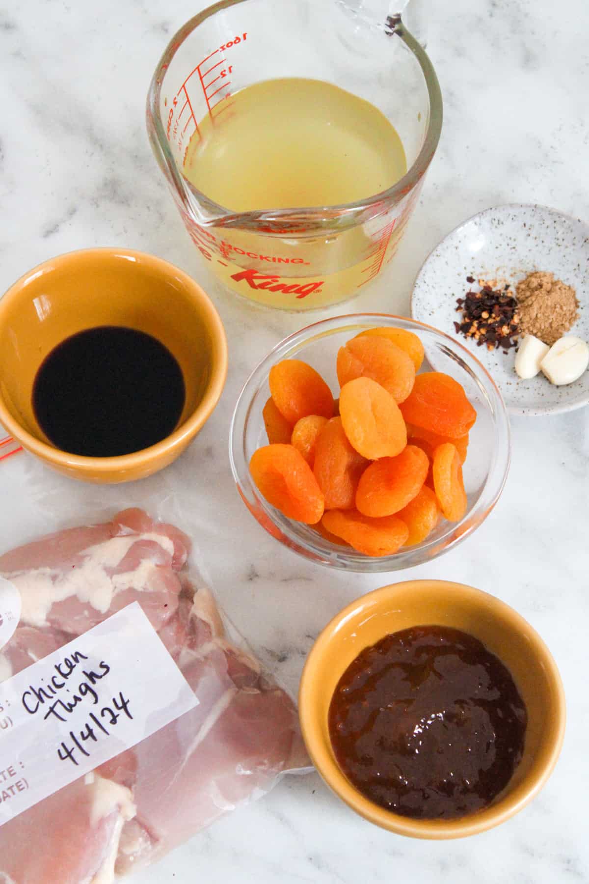 overhead view of apricot chicken ingredients in small bowls on a marble counter top