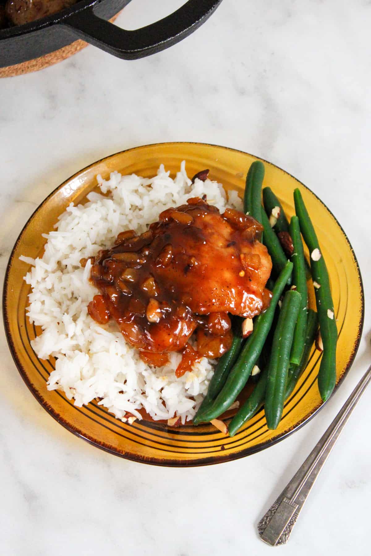 chicken thigh glazed with apricot sauce on a bed of white rice and green beans, served on a retro brown glass plate