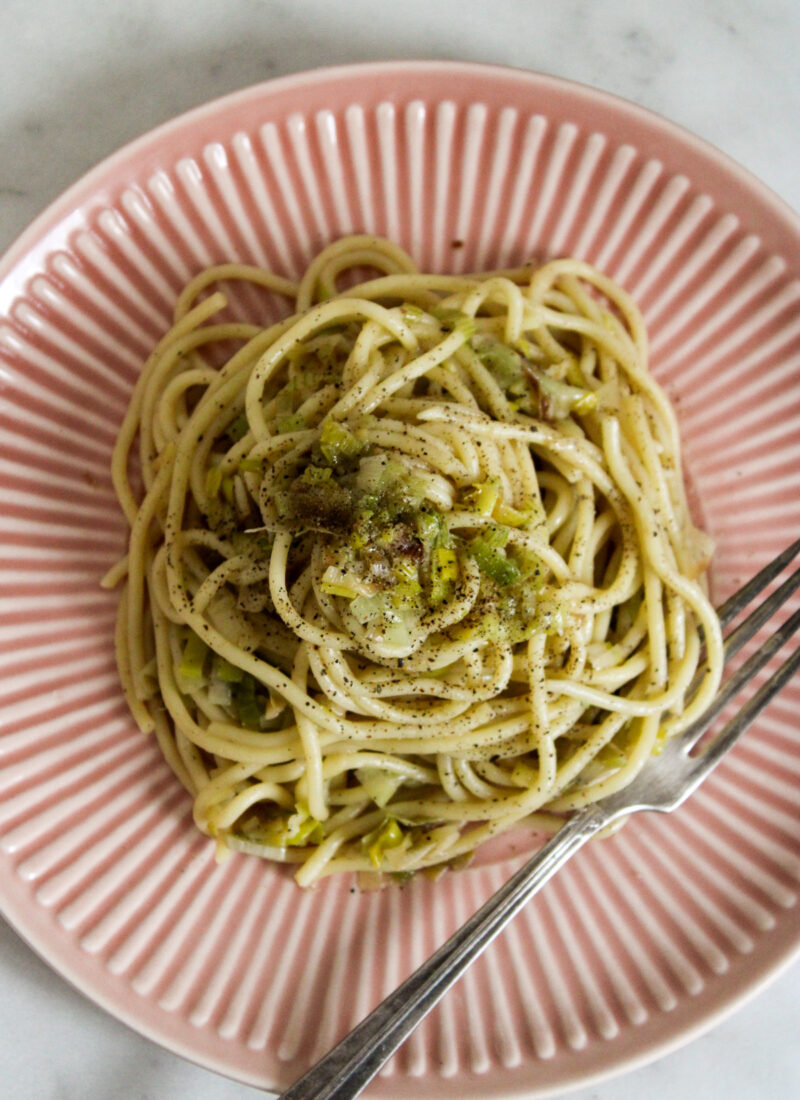 caramelized leek pasta on a pink plate with a fork