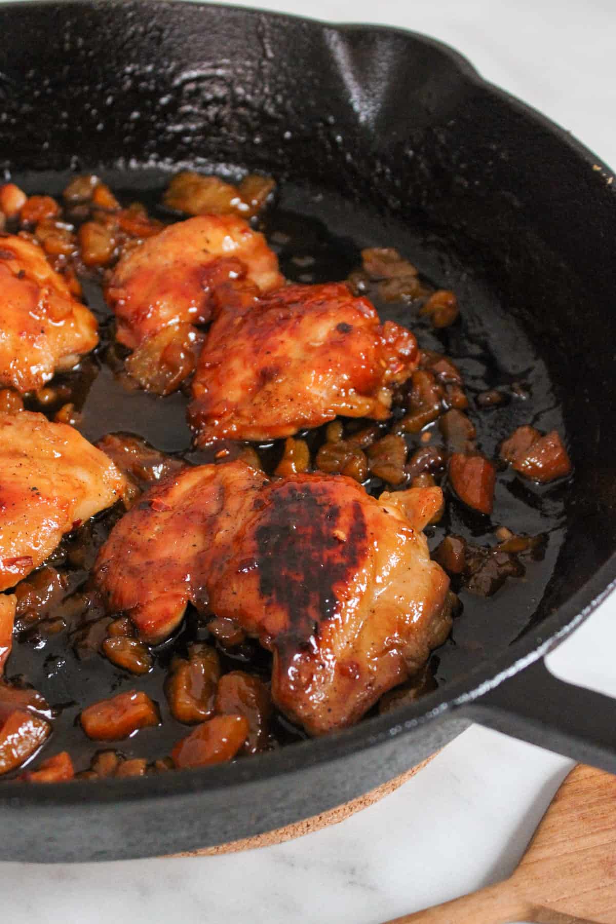 seared chicken thighs in a black cast iron pan, glazed in a sticky apricot sauce