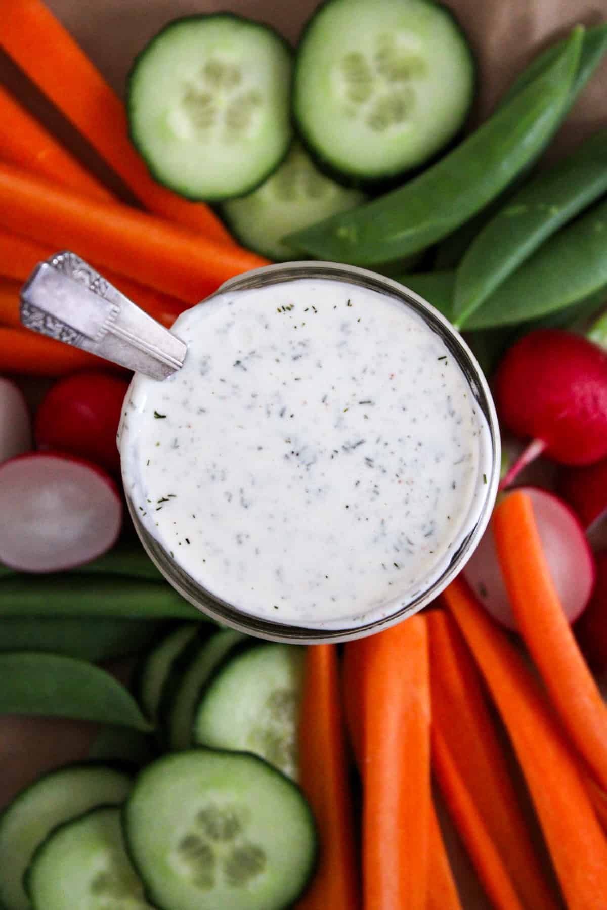 overhead shot of a jar of ranch dressing surrounded by a rainbow of vegetables