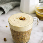 pistachio over night oats in a glass mug on a marble counter