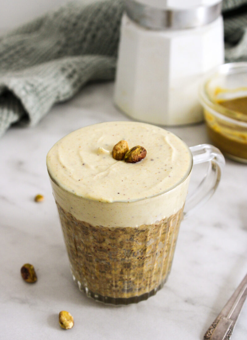 pistachio over night oats in a glass mug on a marble counter