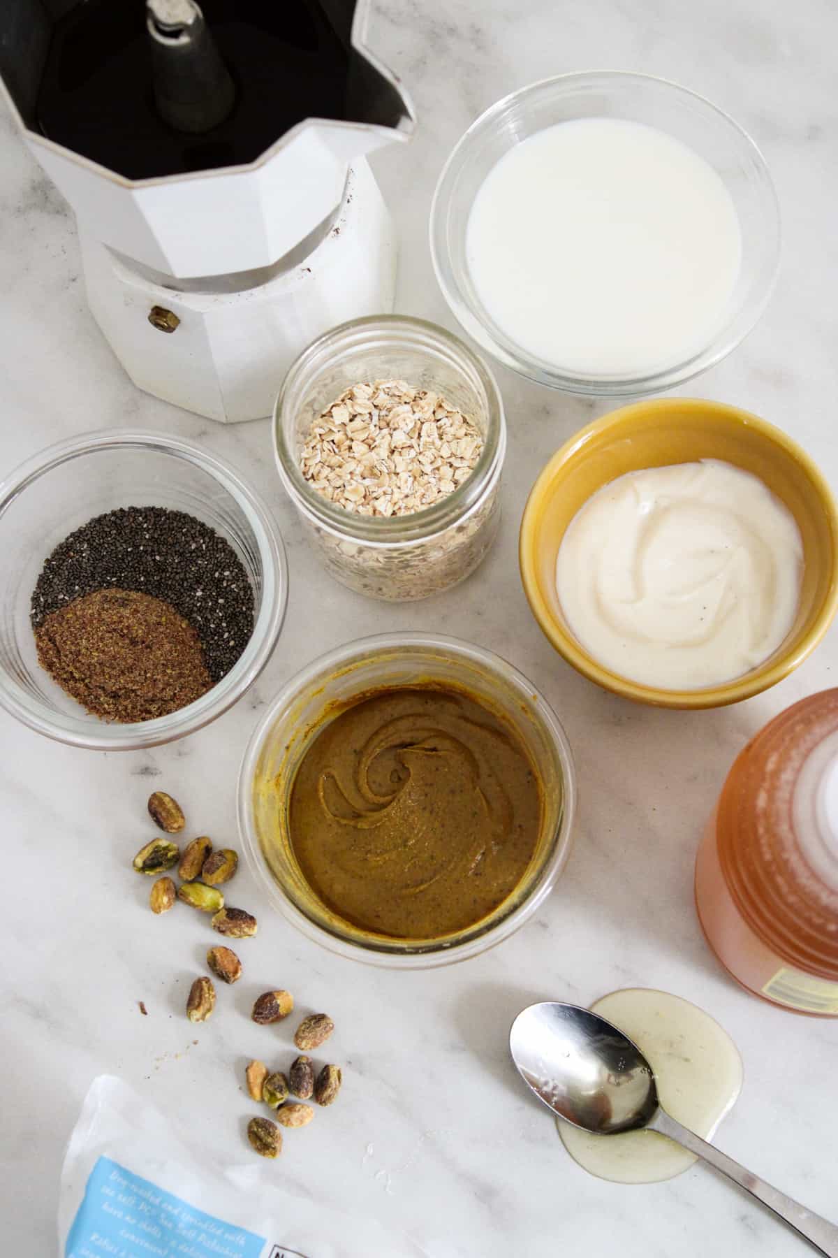 ingredients for pistachio latte overnight oats in small bowls on a marble counter top