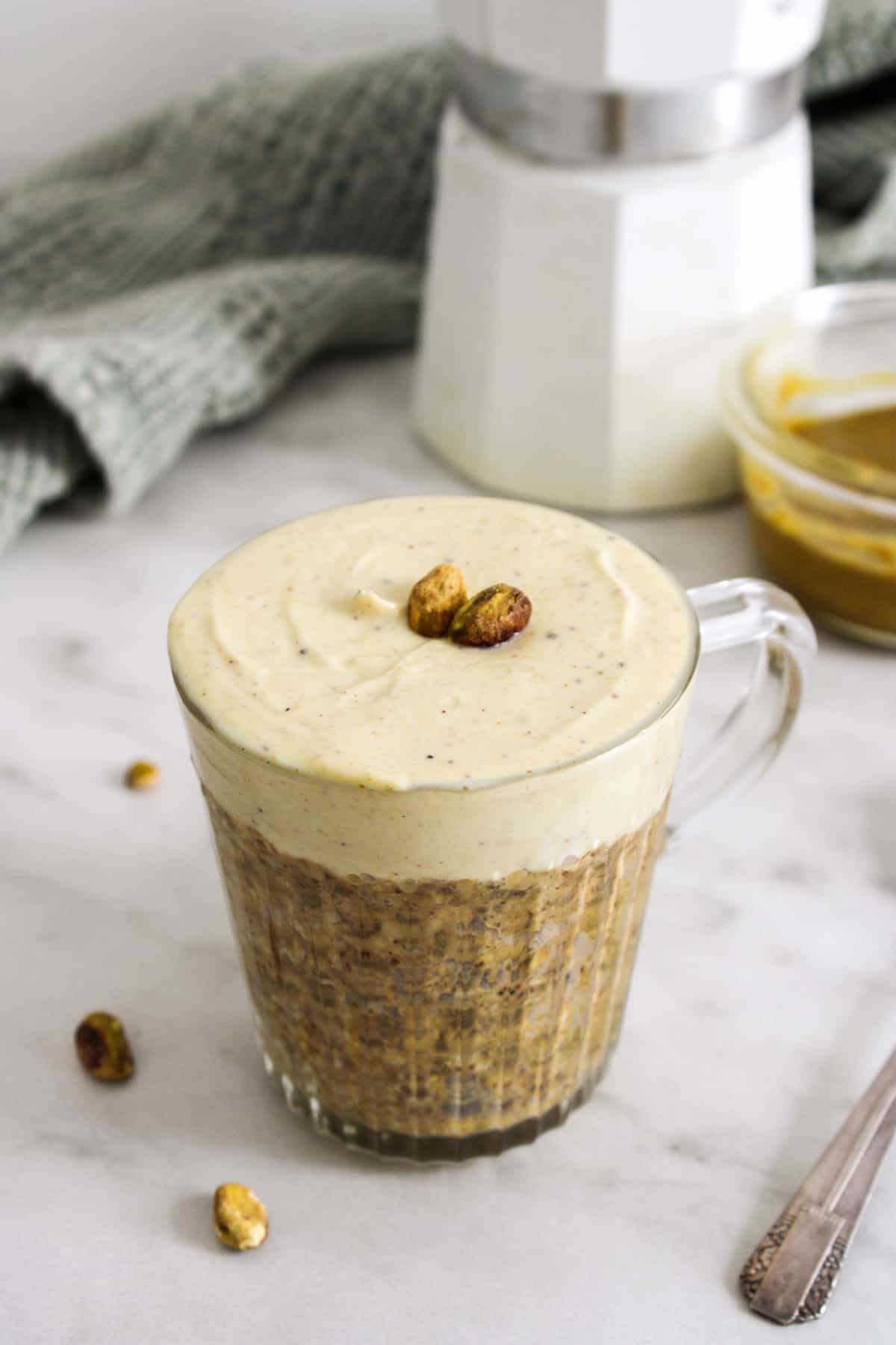 pistachio over night oats in a glass mug on a marble counter