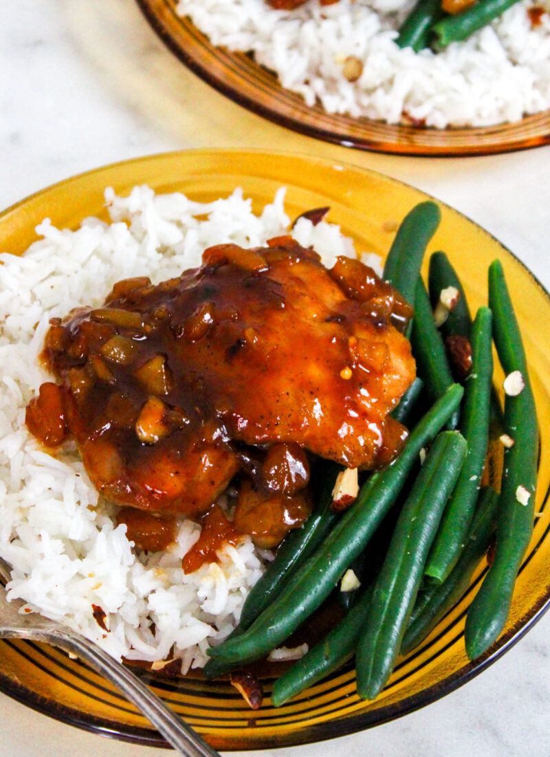 chicken thigh glazed with apricot sauce on a bed of white rice and green beans, served on a retro brown glass plate
