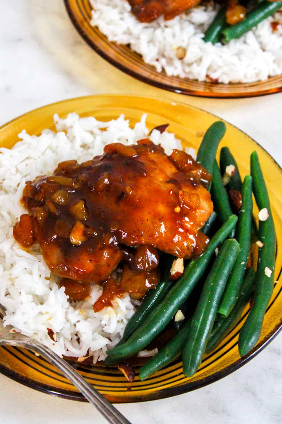 chicken thigh glazed with apricot sauce on a bed of white rice and green beans, served on a retro brown glass plate