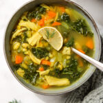 lemon white bean turkey and kale soup in a bowl topped with a lemon slice and dill